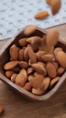 Tahta bir kaseye dökülen taze ve doğal çiğ badem manzarasını yakından izleyin. Sağlıklı ve organik vejetaryen yaşam tarzını temsil eden protein ve besinlerle dolu sağlıklı bir aperatif.