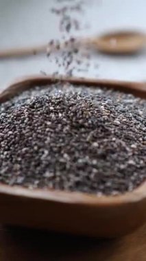 Sağlıklı çiğ çiğ çekirdeklerin yavaş çekimde kare bir ahşap kaseye dökülmesi, vejetaryen süper yiyecekler, sağlıklı beslenme, antioksidan ve vegan diyeti için omega 3 kaynağı kavramı.