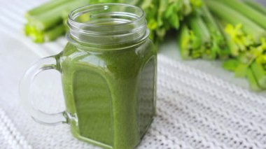 Masa örtüsünde kereviz sapı olan bir kavanozda taze yapılmış yeşil detoks smoothie sağlıklı bir diyet, kilo kaybı ve vitamin ve besin maddeleri için mükemmel bir içecek.