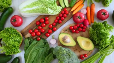 Sağlıklı bir diyet için taze organik sebzelerin renkli seçimi, olgun domatesler, yeşil marul, havuç ve avokado dahil, vejetaryen yemek pişirmek için canlı bir mutfak arka planı yaratır.