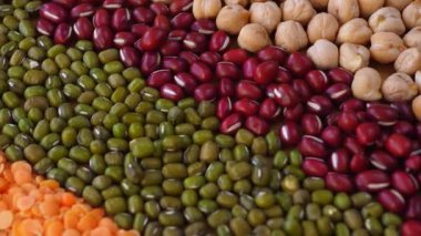 Kırmızı adzuki fasulyesi, yeşil mung fasulyesi, nohut ve farklı türde mercimek gibi çeşitli baklagiller sağlıklı, protein zengini bileşenlerin canlı ve dokulu bir arka planını oluşturur.