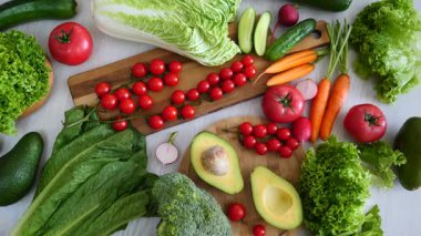 Masadaki salata için taze organik sebzelerle sağlıklı gıda arka planı. Kiraz domatesleri, avokado, marul, havuç ve diğer vitamin açısından zengin vejetaryen malzemeler.