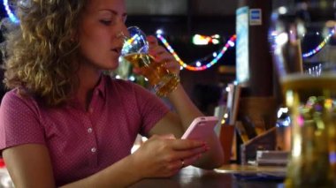Bar Counter bira içme akıllı telefon kullanan kadın