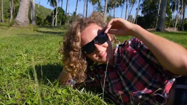 Menina bonita deitada no campo em grama verde. Feliz e sorridente — Vídeo de Stock