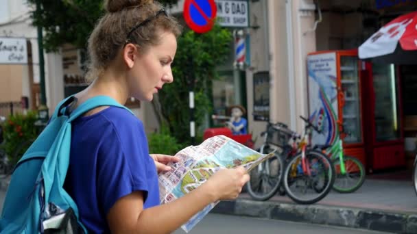 Mujer joven con mapa turístico en la ciudad — Vídeos de Stock