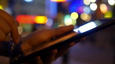 Gece şehir ışıkları karşı dijital Tablet kullanarak eller
