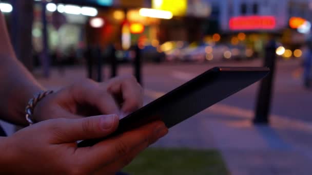 Main féminine en utilisant une tablette dans Night City. Gros plan .