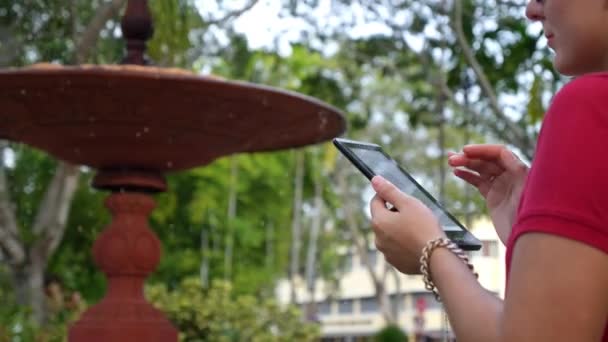 Νεαρή γυναίκα χρησιμοποιώντας Tablet στο πάρκο της πόλης — Αρχείο Βίντεο
