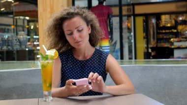 Genç kadın manifatura mesaj cep telefonuyla Cafe