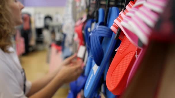 Женщина выбирает шлепанцы в магазине спортивной обуви — стоковое видео