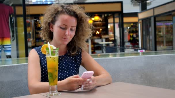 Mooi meisje met behulp van haar mobiele telefoon in café. — Stockvideo