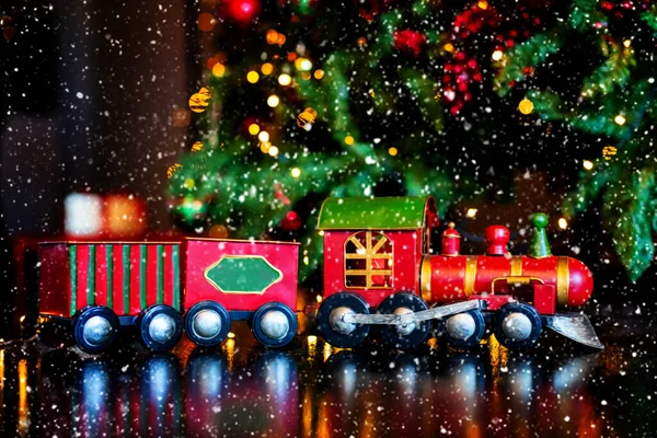 Noel oyuncak treni şık bir şekilde dağılmış Noel ağacında ve arka planda ışıklar