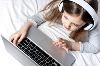 Kulaklıklı liseli kız evde online eğitim, ev eğitimi ve internet iletişimi için dizüstü bilgisayar kullanıyor. Çocuklar uzaktan öğreniyor. Sosyal mesafe. Evde kal..