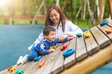 Mutlu gülümseyen Asyalı anne ve çocuk yaz parkında oyun oynuyorlar. Metin için alanı kopyala