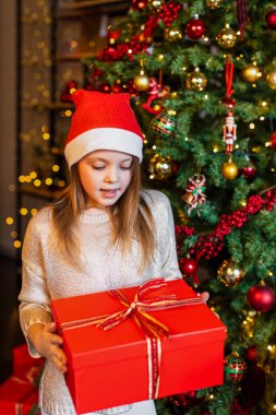 Bir çocuk Noel ağacının arka planında sihirli bir hediye kutusu görünce şaşırır.