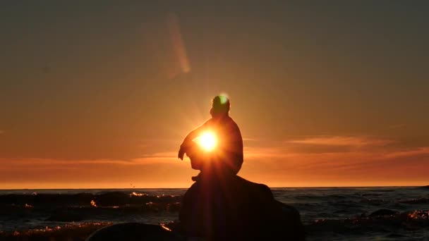 Homme silhouette sur un rocher dans la mer pensée dolly shot au coucher du soleil — Video