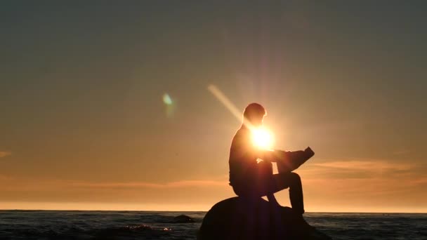 Männersilhouette liest Zeitung auf einer kleinen Insel im Meer — Stockvideo