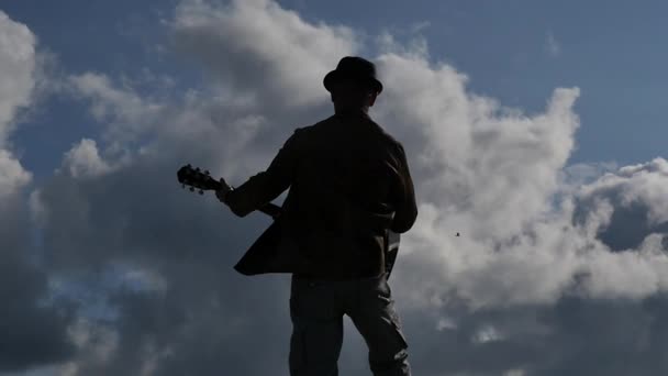 Людина з видом на гітару проти сонця і хмари повільний рух слідувати фокусу — стокове відео