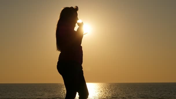 Mujer silueta beber vino cerca del mar tranquilo al atardecer — Vídeo de stock