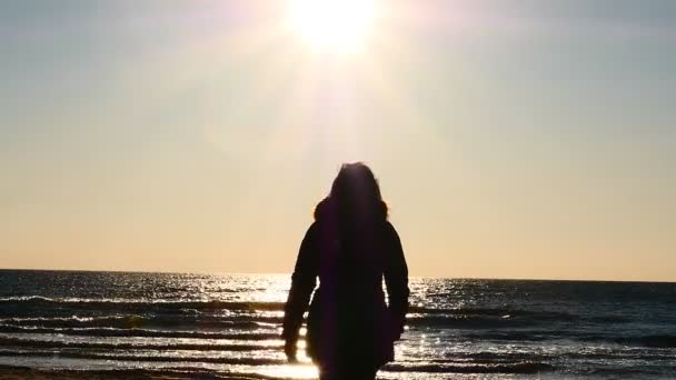 Caldamente vestita donna si muove verso la riva del mare al rallentatore — Video Stock