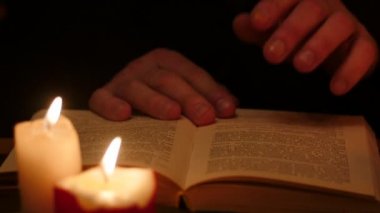 Kitap izole eller yaprak siyah zemin üzerine okuma ve yavaş hareket mumlar