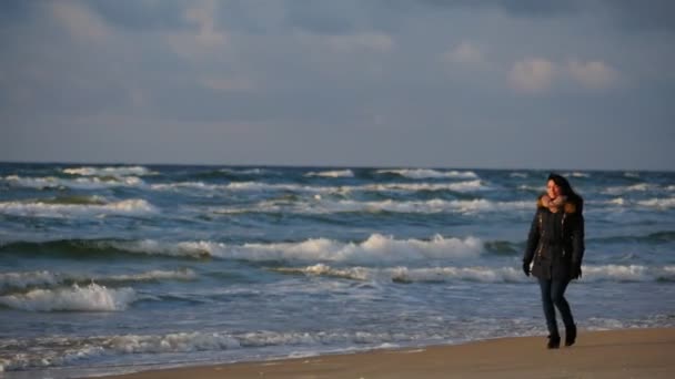 Vrouw in warme kleren beweegt langs winter zee lijn slow motion — Stockvideo