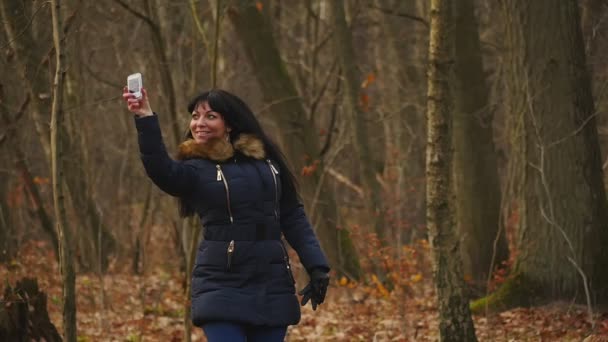 Ung kvinna snurrar med mobiltelefon i höst skogen slow motion — Stockvideo