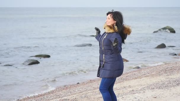 Ładna kobieta w zimie tkaniny pozowanie jak pussycat w morze linii slow motion — Wideo stockowe