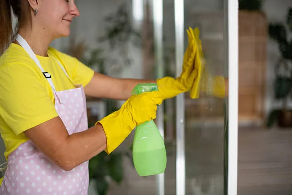 Professional cleaning of the bathroom and toilet. Cleanliness and hygiene at home. Cleaning service and housekeeping. Hand in green and yellow latex gloves. Rubbing the bathroom and taps