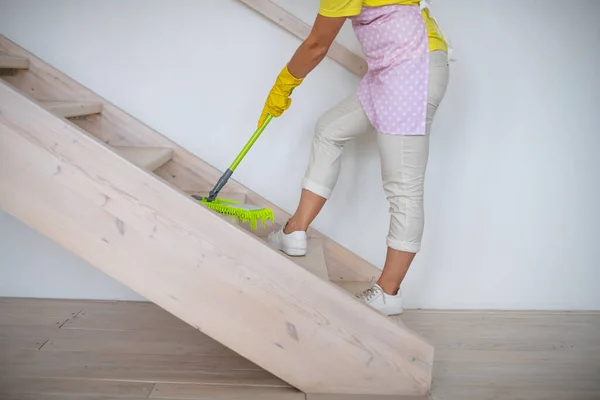 A professional cleaner washes the floor with a mop. A green rag rubs the floor. Cleaning of apartments and premises. Cleaning equipment and supplies