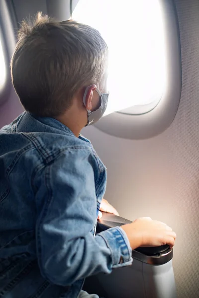 Chłopiec Masce Medycznej Siedzi Fotelu Samolotu Mały Pasażer Patrzy Otwór — Zdjęcie stockowe