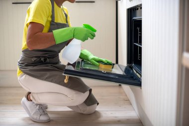 Profesyonel mutfak temizliği. Hizmetçi fırını yıkar. Lastik eldivenli bir kız toprağı siliyor. Temizlik ve hijyen.