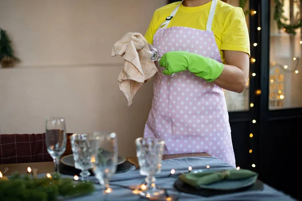 General cleaning before the winter holidays Christmas and New Year. Professional housekeeping service. Cleaning lady in yellow uniform and gloves cleans the glass