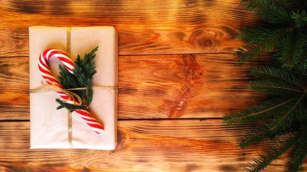 Χριστουγεννιάτικο δώρο με καραμέλες που περιβάλλεται από κλαδιά ελάτης με λαμπερό γιρλάντες — Φωτογραφία Αρχείου
