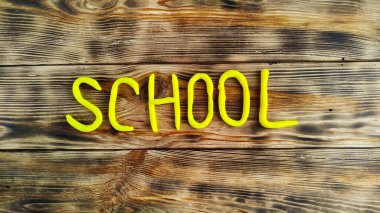 Ahşap bir arka planda plastikten oyulmuş bir yazı okulu.