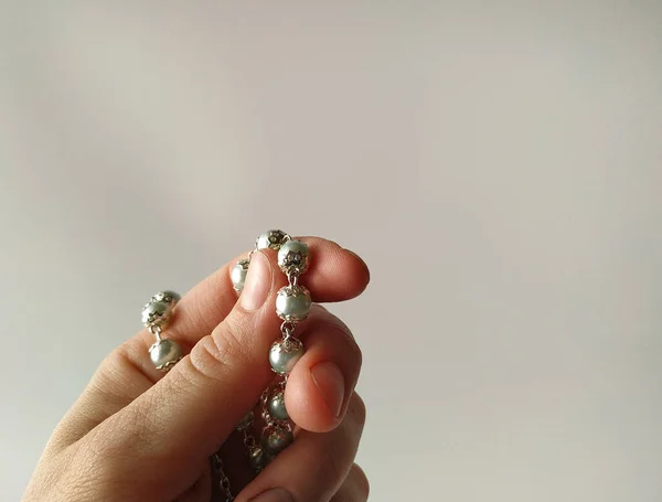 Katholischer Rosenkranz zum Gebet in weiblicher Hand auf weißem Hintergrund — Stockfoto