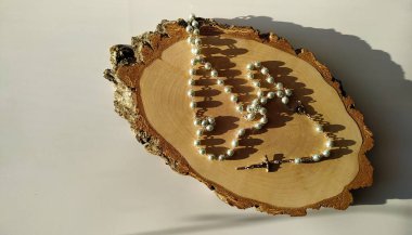 Güneş altındaki bir huş ağacının ahşap kesiminde dua etmek için Katolik tespihi.