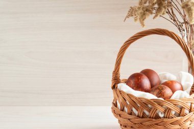 Hasır bir sepette doğal boyalarla boyanmış Paskalya yumurtaları. Paskalya arkaplanı