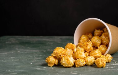 Yeşil arka planda kağıt bardakta patlamış mısır