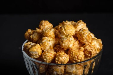 Koyu arkaplanda cam bir tabakta patlamış mısır.