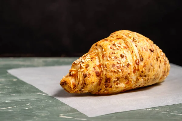 Croissant with sesame seeds on a green background