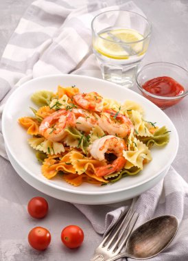 Beyaz arka planda karides, domates ve baharatlı makarna.