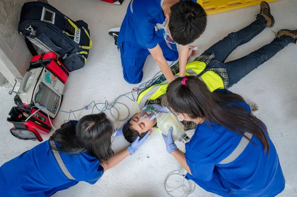 Acil tıp ekipleri, otomatik dış defibrilatör (AED) kullanarak ve oksijen sağlayarak bilinçsiz hastalara yardım ediyor. İnşaat alanındaki baygın işçilerin kurtarılması sırasında