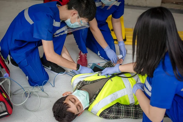 Acil tıp ekipleri, otomatik dış defibrilatör (AED) kullanarak ve oksijen sağlayarak bilinçsiz hastalara yardım ediyor. İnşaat alanındaki baygın işçilerin kurtarılması sırasında