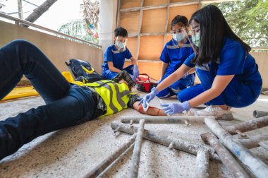 İnşaat işçisinin işyerinde fiziksel yaralanma. Acil sağlık ekipleri ilk olarak inşaat alanında kaza geçiren bir inşaat işçisine yardım ediyor..