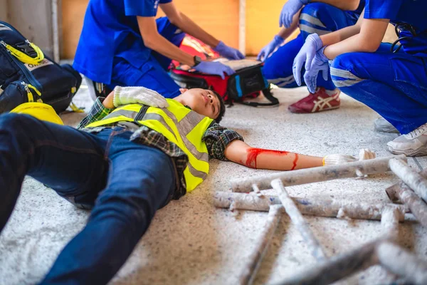 Physical injury at work of construction worker. Emergency medical teams are first aiding a construction worker who has an accident at a construction site.