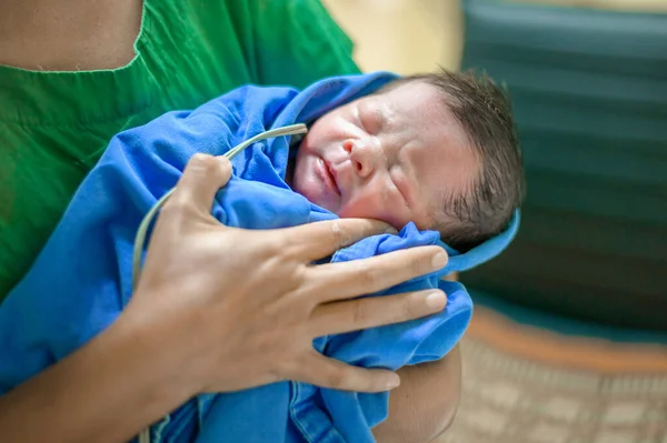 One day old newborn : A newborn baby is in the arms of a nurse after giving birth in a hospital delivery room.