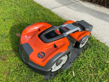 Orlando, FL. / USA - 9 / 30 / 20: Bir Husqvarna otonom çim biçme makinesi Orlando, Florida 'daki Laureate Park mahallesinde bir gölün yakınında biçiyor