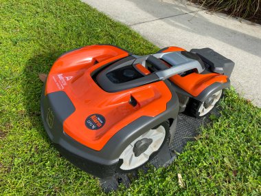 Orlando, FL. / USA - 9 / 30 / 20: Bir Husqvarna otonom çim biçme makinesi Orlando, Florida 'daki Laureate Park mahallesinde bir gölün yakınında biçiyor
