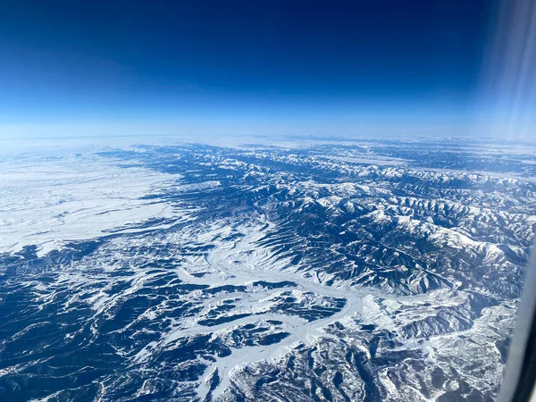 Uma Vista Aérea Uma Janela Avião Montanhas Neve Nuvens Céus — Fotografia de Stock